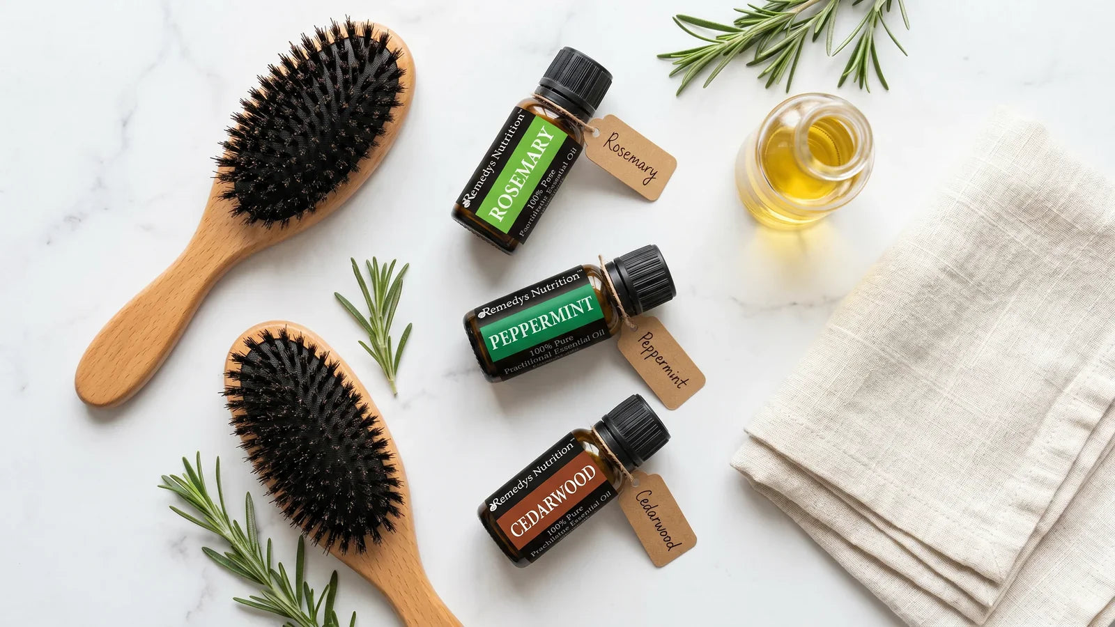 Bathroom flat lay of amber rosemary peppermint and cedarwood oil bottles with wooden hairbrush on marble