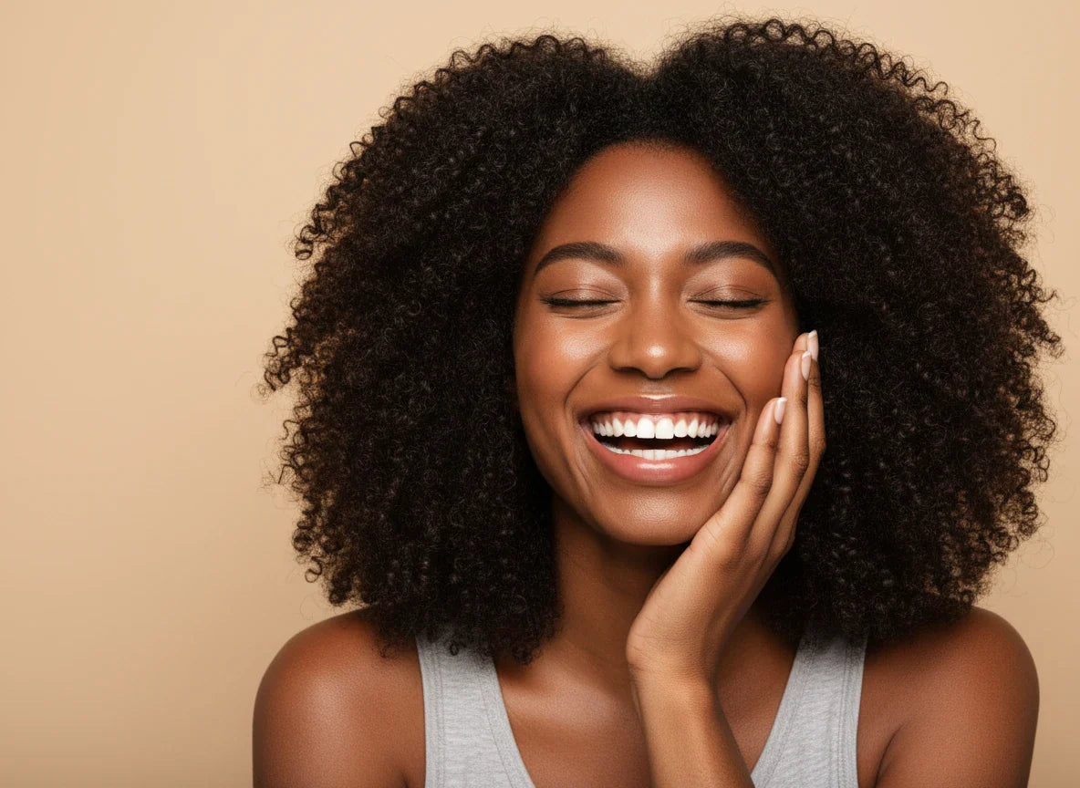 Radiant African American woman with a beautiful afro, joyfully laughing and showing an expressive smile, symbolizing the renewed energy from using vitamin c for adrenal fatigue.