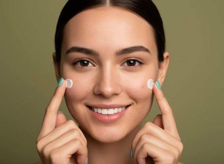 Close-up: Young woman with natural skin showing typical signs of zinc deficiency, such as acne and blemishes, smiling while holding skincare cream against a muted olive green background.